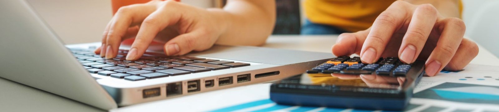 Hands typing on a keyboard and calculator. 