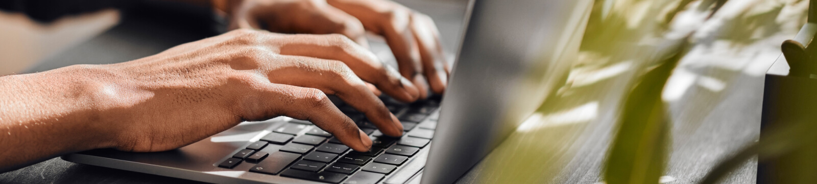 close-up of hands typing on a laptop keyboard