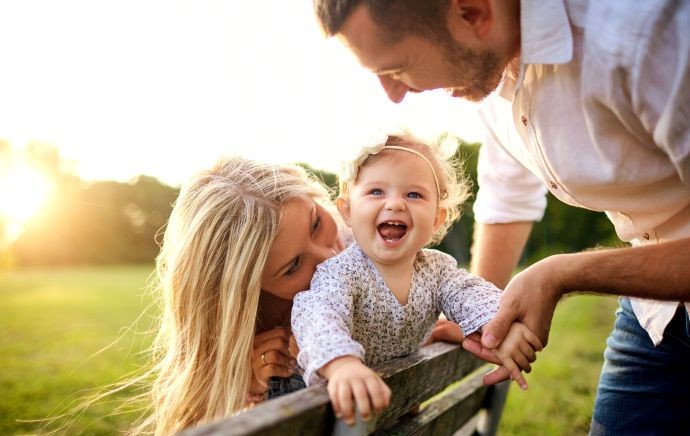 man, woman, and baby playing outside smiling